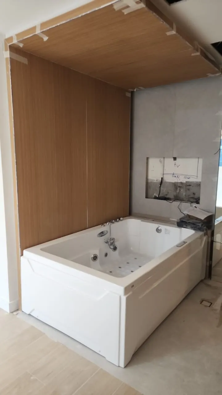 The master bathroom during the works: the bath set in its new timber-lined alcove, with the TV recess still open above it