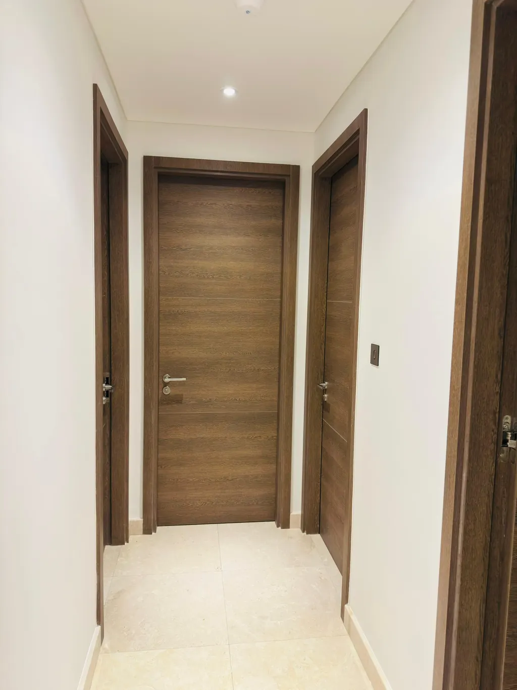 Hallway with timber doors and a stone floor in a Dubai Maritime City apartment