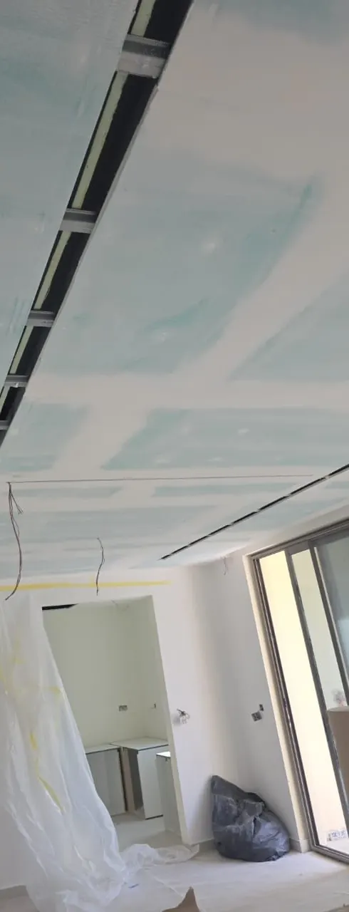Gypsum ceiling with a shadow gap and slot diffusers being boarded