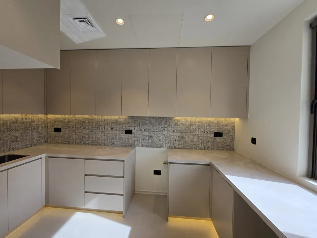 Kitchen in warm grey with a lit plinth and patterned splashback