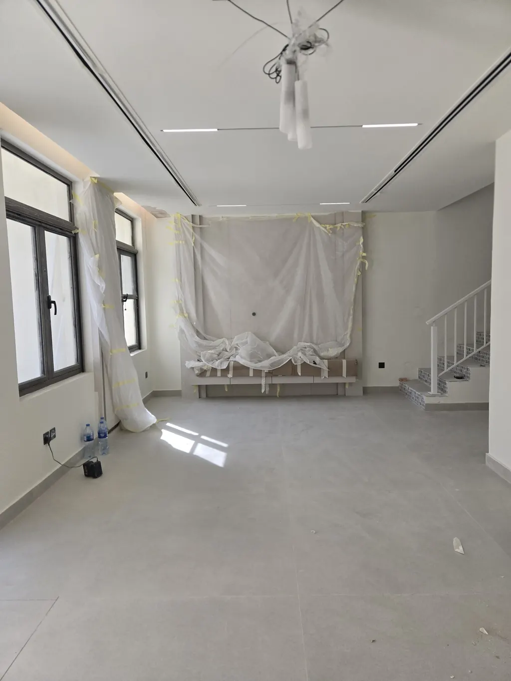 The living room near the end of the works, looking to the media wall under protection, with the new floor laid and the slot diffusers in the ceiling
