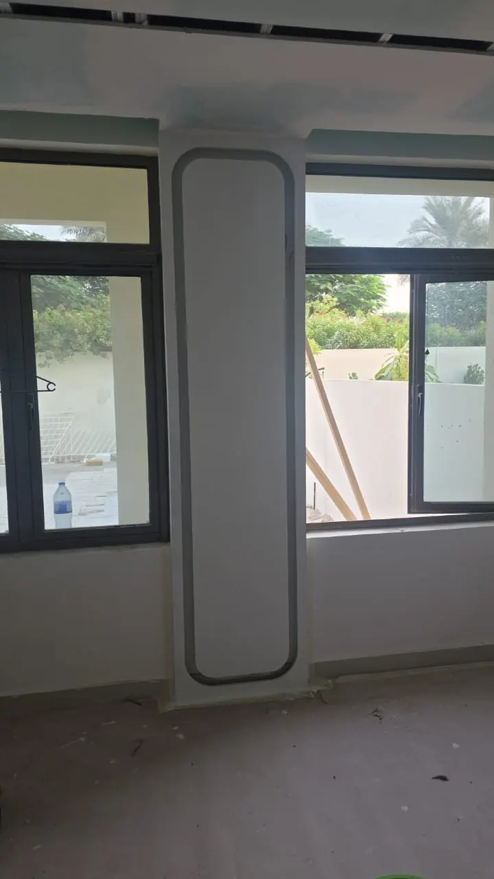 The living room window wall during the works: the rounded wall panel formed in plaster between the two windows, before its light was fitted