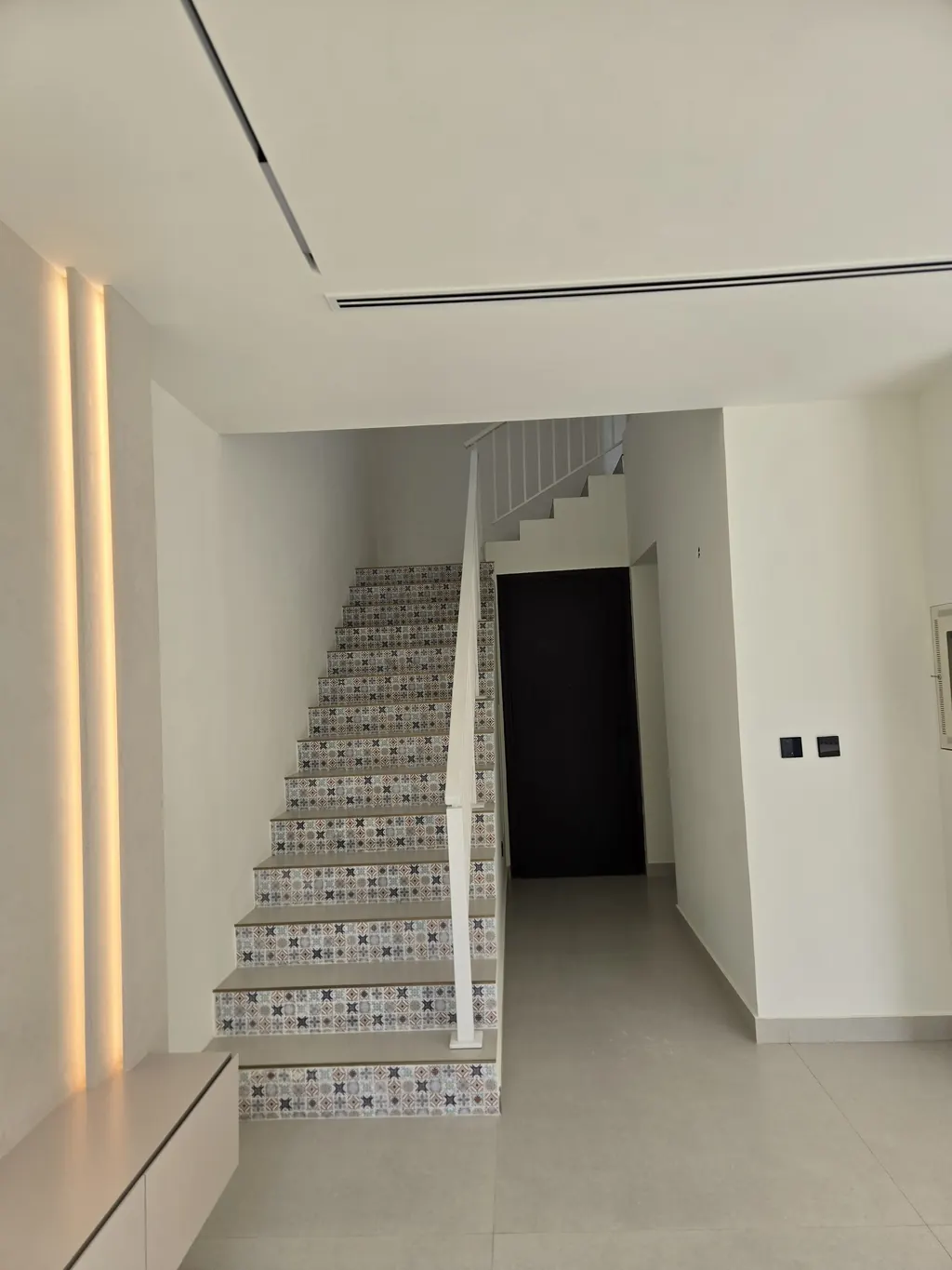 Staircase re-tiled with patterned risers beside a lit wall