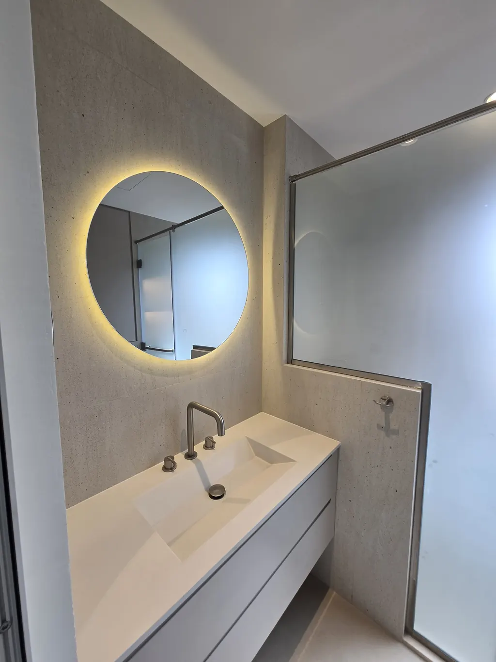 Vanity with a backlit round mirror and integrated basin